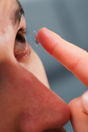 Correcting eye wellnesses with optical contact lenses. Man inserts a contact lens into eye for myopia treatmentの写真素材