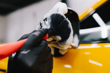 Detailing procedure of applying a soapy solution to the car's mirror using a brush. Meticulous car detailing at the carwashの写真素材