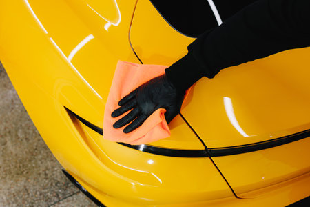 Microfiber hand cleaning and washing sports car using microfiber towel in garage. Manual washing and...