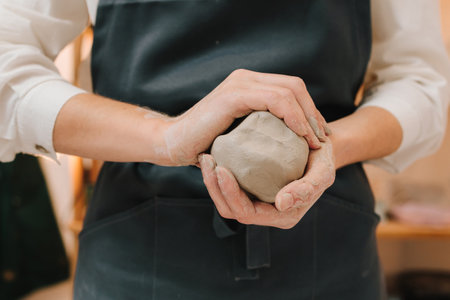 Girl potter is creating a ceramic ware in the workshop. Woman potter works with wet clay in the...