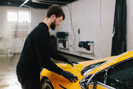 Washing car with sponge with soap foam for detailing at the car service. Preparing a tuned car for detailingの写真素材
