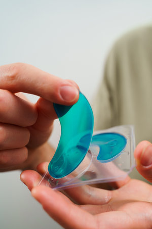 Pampering anti-aging moisturizing eye mask for skin care concept. Male hands hold a collagen blue...