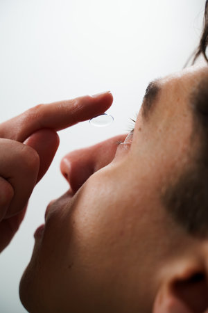 Man is wearing daily contact lenses for eyesight correction. Vision correction with eye contact lenses chosen by ophthalmologistの写真素材