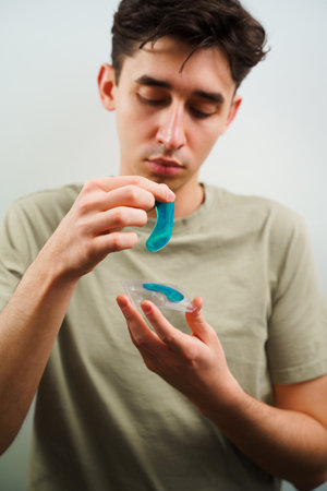 Man takes on hydrogel patches for skincare routine. Using male cosmetic to reduce circles under the eyesの写真素材