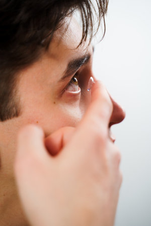 Man inserts a contact lens into eye for myopia treatment. Correcting eye wellnesses with optical contact lensesの写真素材