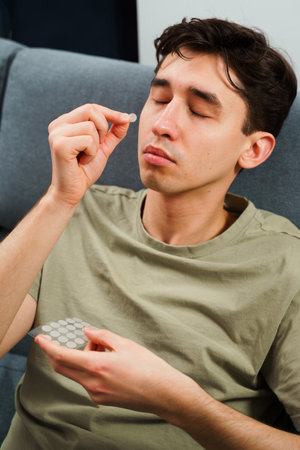 Young guy sticking acne patches to forehead to clean skin from zits. Using acne patches for facial skincareの写真素材