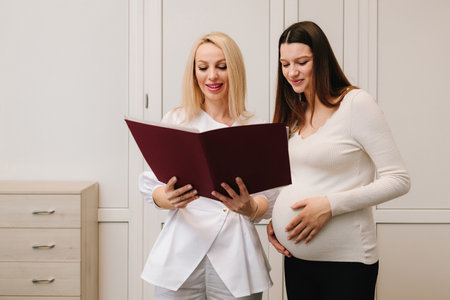 Gynecologist is showing analysis tests for pregnancy checkup. Gynecologist doctor reports medical results to pregnant patientの写真素材
