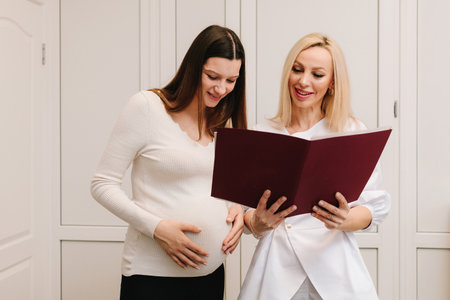 Gynecologist doctor reports medical results to pregnant patient. Gynecologist is showing analysis tests for pregnancy checkupの写真素材