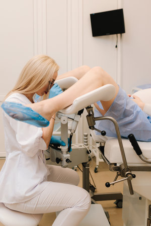 Woman patient is examining by gynecologist in the gynecological chair during checkup in the clinic. Scheduled examination of pregnant in gynecology clinicの写真素材