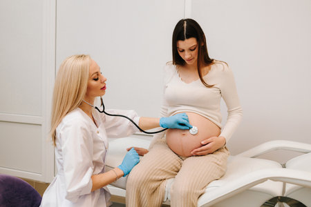 Gynecologist examination pregnant belly for baby with medical stethoscope in the maternity center. Pregnancy consult about fetus health on the appointment in gynecology clinicの写真素材