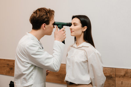 Ophthalmoscopy. Ophthalmologist examines the eyes of woman with ophthalmoscope. Ophthalmology consultation with an optometrist in a medical clinicの写真素材