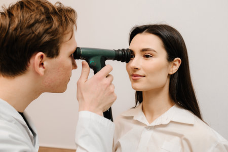 Ophthalmoscopy. Ophthalmologist examines the eyes of woman with ophthalmoscope. Ophthalmology consultation with an optometrist in a medical clinicの写真素材