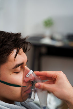 Patient inhaling through nebulizer for pneumonia treatment. Breathing with nebulizer for home virus treatmentsの写真素材