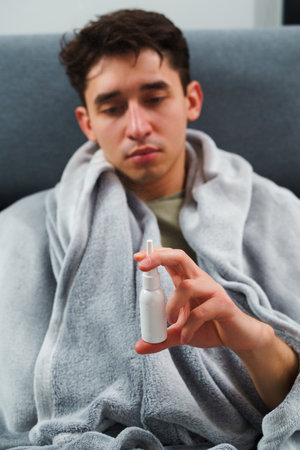 Man is taking medical pills and sprays by doctor's prescription at home. Sick patient takes nose...