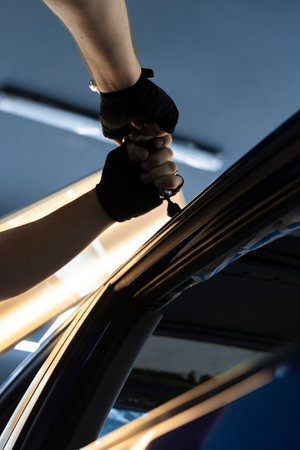 Using pulling tool for PDR on a glossy car roof, adjusting pressure precisely. Expert uses advanced pulling tool to restore metal shape without repaintingの写真素材