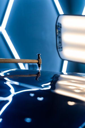Controlled taps with a knockdown tool reshape metal warped by hail. PDR technician uses a knockdown tool and hammer combo to correct hail dents. Focused strikes realign metal without harming paintの写真素材