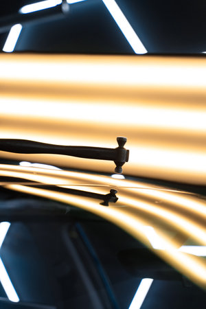PDR Accurate paintless car dent removal. PDR technician holds a specialized hammer against a reflection light board to check dent correction on the hoodの写真素材
