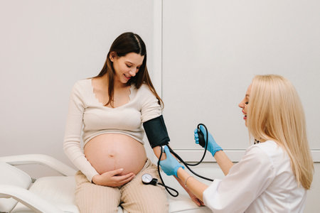 Gynecologist measures blood pressure for pregnant patient in the maternity center. High pressure problem during pregnancyの写真素材
