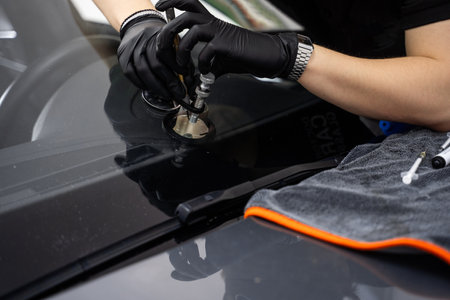Handheld windshield crack repair for stable resin injection. Repair bridge stabilizes injector while resin is pressed into chip. Suction mount holds steady pressure during curingの写真素材