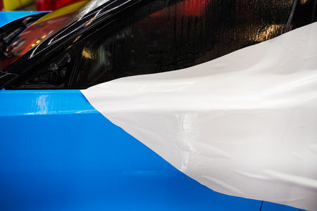 Detailer removes the liner from the PPF while applying water to the panel for clean adhesion. Paint Protection Film PPF Application Processの写真素材