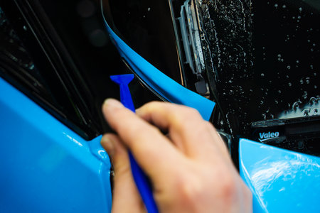 Micro squeegee to press blue vinyl wrap deep into tight vehicle trim gaps. Micro squeegee tool...