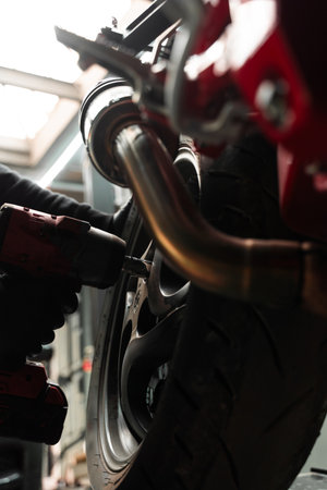 Motorcycle Rear Wheel Removal. Mechanic uses high-torque impact wrench to remove the rear wheel of sportbike. Rear wheel disassembly uses high-torque impact wrenchの写真素材