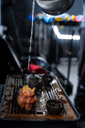 Hot water is poured onto a vibrant dragon tea pet during a Gongfu tea ceremony. Water flows onto a...