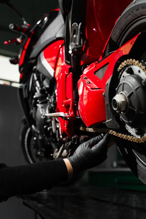 Chain tensioning at motorcycle maintenance service. Motorcycle chain maintenance is essential for smooth riding and drivetrain longevity. Chain tuning improves torque delivery and rear performanceの写真素材