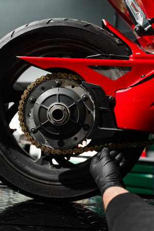 Chain tensioning at motorcycle maintenance service. Motorcycle chain maintenance is essential for smooth riding and drivetrain longevity. Chain tuning improves torque delivery and rear performanceの写真素材