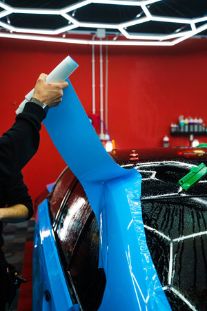 Wet PPF Wrapping on Car Panel in detailing center. Protective film layering during PPF wrap detailing to protect the car surface from scratches and UVの写真素材