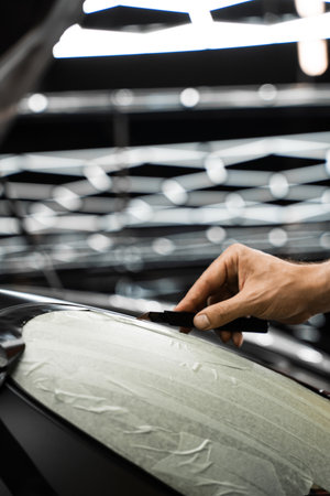 Wrapping vinyl requires perfect tension and accurate blade work for high-end detailing. Vinyl film is carefully applied and trimmed with a blade for flawless vehicle wrapping resultsの写真素材
