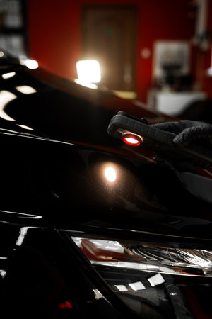 Car paint inspection using detailing inspection light before polishing or ceramic coating. Swirl finder light to detect paint issues on black car in a detailing studio. Car Paint Inspectionの写真素材
