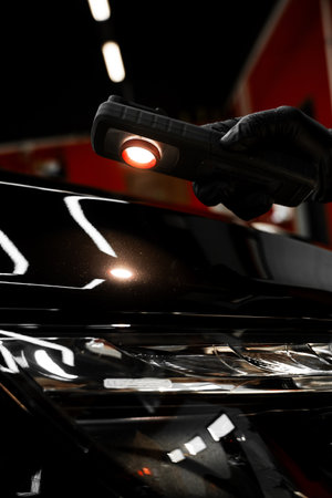 Swirl finder light to detect paint issues on black car in a detailing studio. Car Paint Inspection. Car paint inspection using detailing inspection light before polishing or ceramic coatingの写真素材