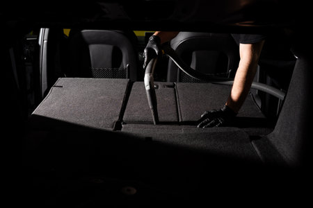 Trunk and cargo area deep cleaning. Detailers vacuum a flat cargo floor to lift away hidden dirt and allergens. Powerful vacuuming of the rear compartment removes deep-seated dust and debrisの写真素材