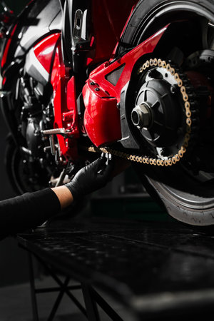 Motorcycle chain maintenance is essential for smooth riding and drivetrain longevity. Chain tuning improves torque delivery and rear performance. Chain tensioning at motorcycle maintenance serviceの写真素材