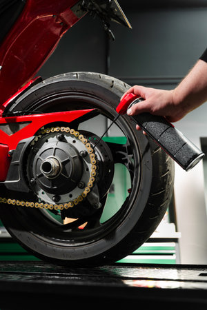 Motorcycle Chain Lubrication with Oil. Oiling motorcycle chain helps reduce wear, prevent rust, and ensure clean drivetrain for top riding performance. Clean oil spray is applied to motorcycle chainの写真素材
