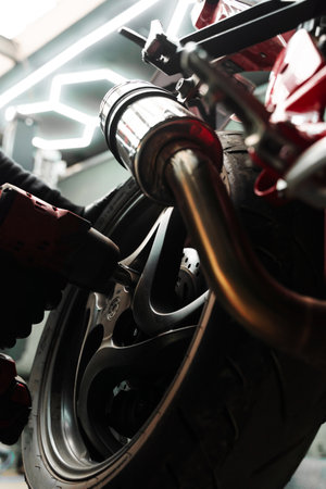 Rear wheel disassembly uses high-torque impact wrench. Mechanic uses high-torque impact wrench to remove the rear wheel of sportbike. Motorcycle Rear Wheel Removalの写真素材