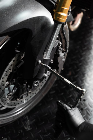 Mechanic performs front suspension service on motorcycle, adjusting forks for precision handling. Fork maintenance improves shock absorption, control, and ride stability on the roadの写真素材