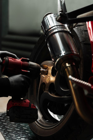 Motorcycle Rear Wheel Removal. Mechanic uses high-torque impact wrench to remove the rear wheel of sportbike. Rear wheel disassembly uses high-torque impact wrenchの写真素材
