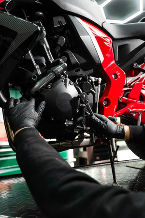 Motorcycle crankcase inspection with ratchet wrench ensures performance efficiency. Mechanic working on motorcycle crankcase during full maintenance inspectionの写真素材