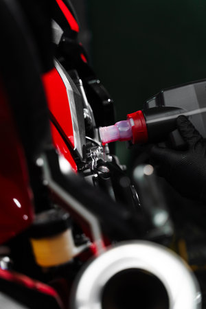 Precision oil fill operation on a red sportbike to ensure proper engine lubrication. Motorcycle Oil Refill. Replacing engine oil in a sports motorcycle to ensure top performance and engine longevityの写真素材