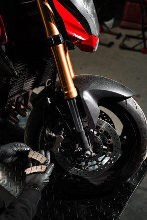 Front Brake Pad Replacement on Red Sport Motorcycle. Front brake pads are inspected and swapped out for better braking response. Pad replacement prevents disc damage and improves controlの写真素材