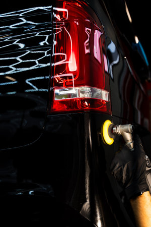 Aggressive paint correction using rotary polisher and hard foam pad removes deep swirls and oxidation on black paint. Detailer performs cutting-stage polishing with rotary machineの写真素材