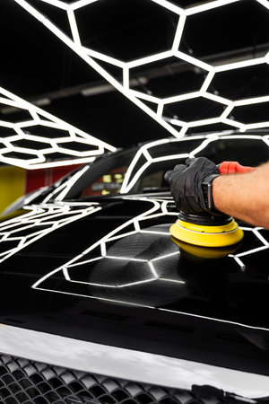 Car hood being polished with yellow pad. Paint polishing in active motion. Paint polishing to eliminate swirl marks and restore deep gloss. Detailing car for sealant or ceramic applicationの写真素材