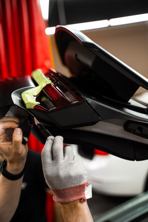 Technician trims car wrap using sharp razor blade ensures accurate vinyl wrap cutting. Precision Cutting with Razor During Car Wrap Installation. Detail work during vinyl wrap applicationの写真素材