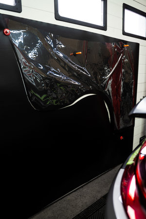 Vinyl wrap is manually cut using stencil over the film for precise shape replication. Vinyl film is trimmed using template directly placed on top. Manual Vinyl Wrap Cutting Using Physical Stencilの写真素材