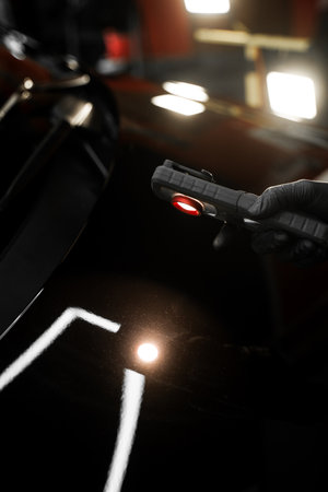 Swirl finder light to detect paint issues on black car in a detailing studio. Car Paint Inspection. Car paint inspection using detailing inspection light before polishing or ceramic coatingの写真素材