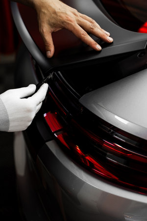 Vinyl Application in Progress in detailing. Vinyl film is trimmed with sharp blade to ensure seamless edges without gaps or tears. Manual vinyl cutting for perfect fitment and clean visual resultsの写真素材