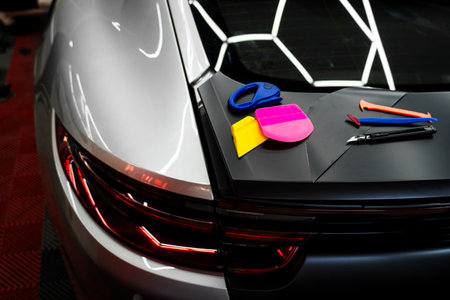 Vinyl wrapping tools and colorful applicators. Blades, scrapers, and squeegees enable smooth and accurate wrap work on complex curves and body lines. Set of Vinyl wrapping Tools on the car.の写真素材