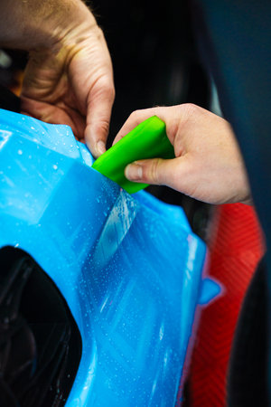 Wet PPF Wrapping on Car Panel in detailing center. Protective film layering during PPF wrap detailing to protect the car surface from scratches and UVの写真素材